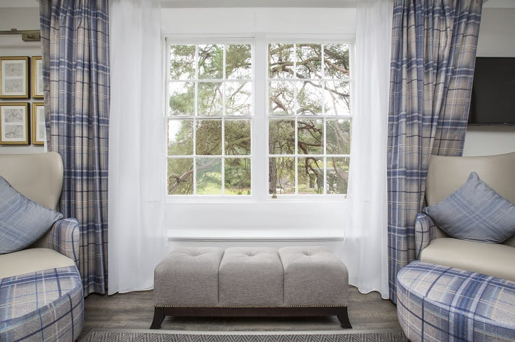 Photograph of a white window of a hotel bedroom with two grey/blue armchairs either side