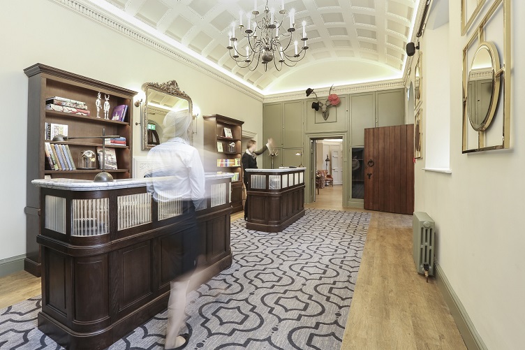 Photograph of the traditional lobby of boutique hotel Wotton House Surrey with concierge in motion