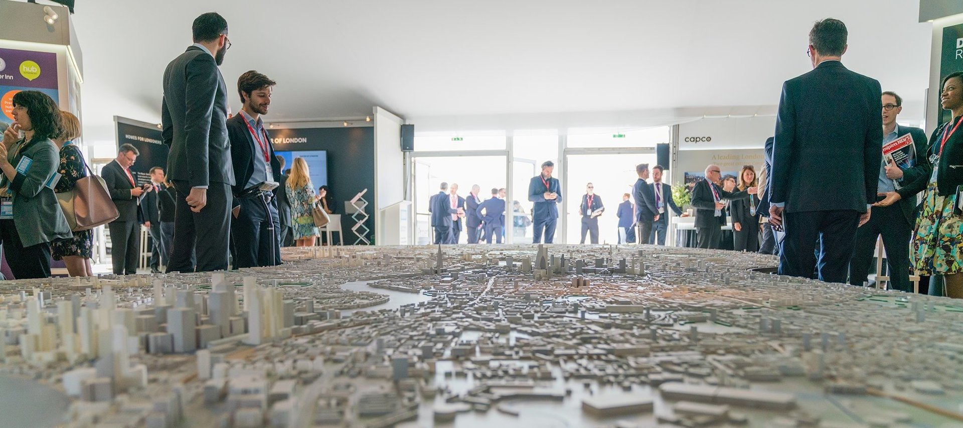 MIPIM conference delegates standing around a miniature model of London UK