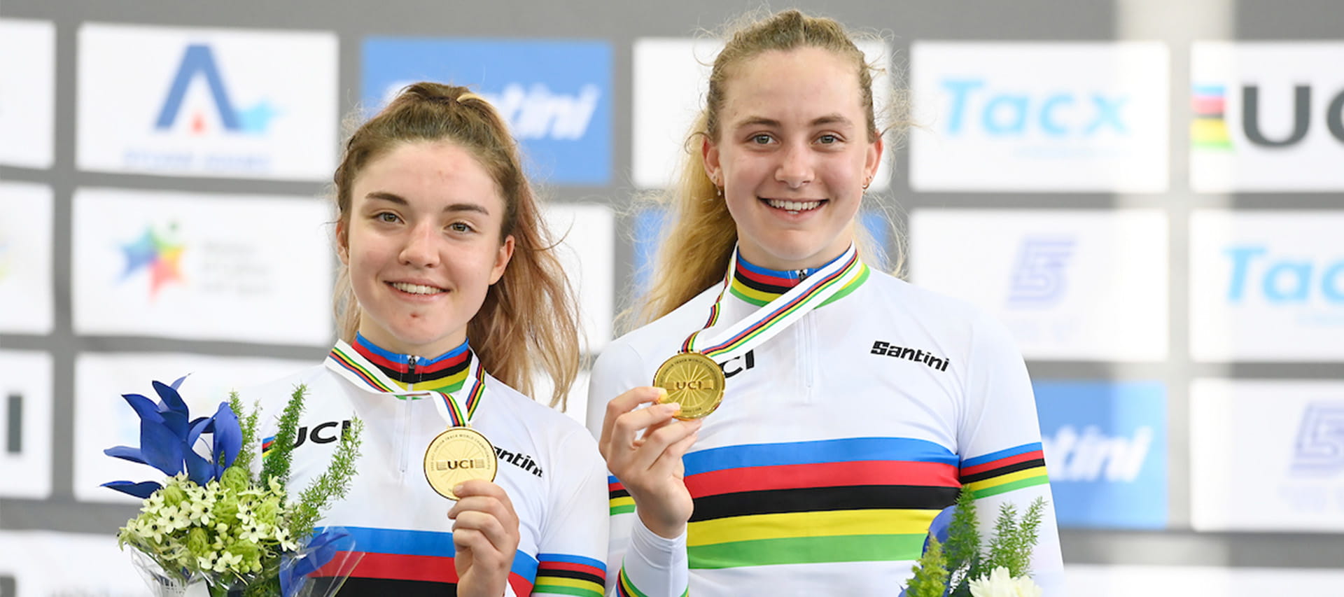 Grace Lister and Zoe Backstedt holding up their medals after their Madison win at the world championships