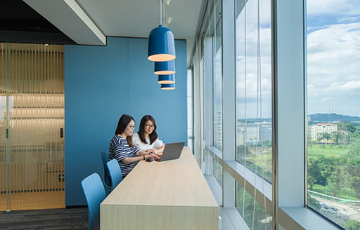 Employees working collaboratively by the window in the office refurbished by ISG for Chinese Tech Giant in Singapore