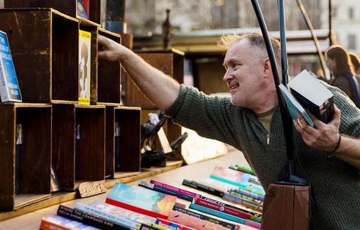 Owner organising displays at Word on the Water boat bookshop Kings Cross London