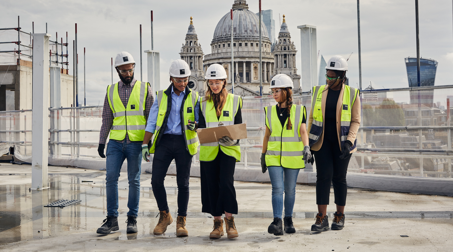 Group of ISG early careers employees in PPE working on a construction site rooftop overlooking St Paul's Cathedral London