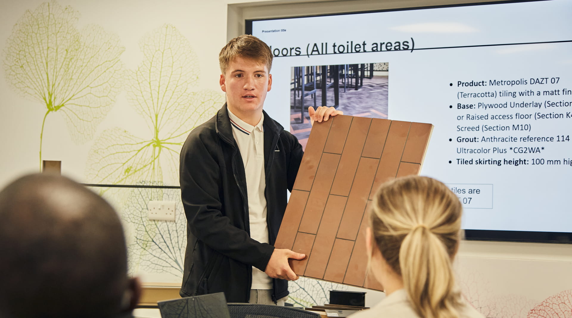 Photograph of student giving presentation with building materials