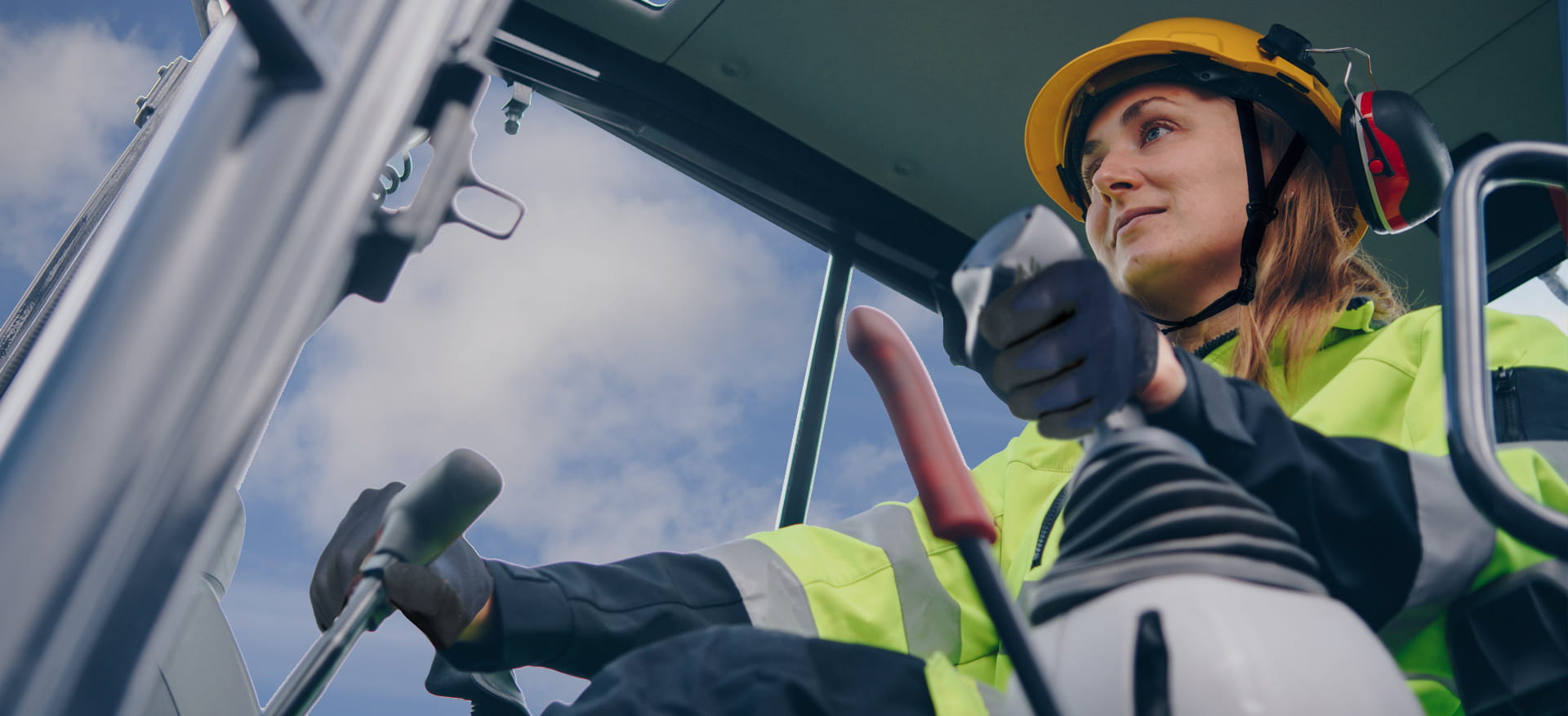 Woman operating a crane in hard hat and high vis