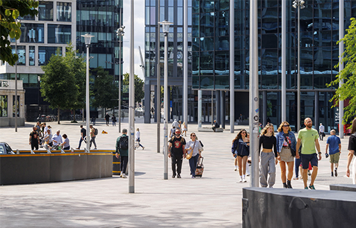 A group of people pass through Cardiff Central Square. 