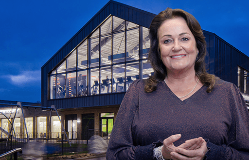Sarah stands in front of an Alliance Leisure centre at night.