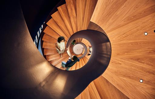 Aerial view of a wooden spiral staircase with office workers walking down it at Freshfields delivered by ISG UK