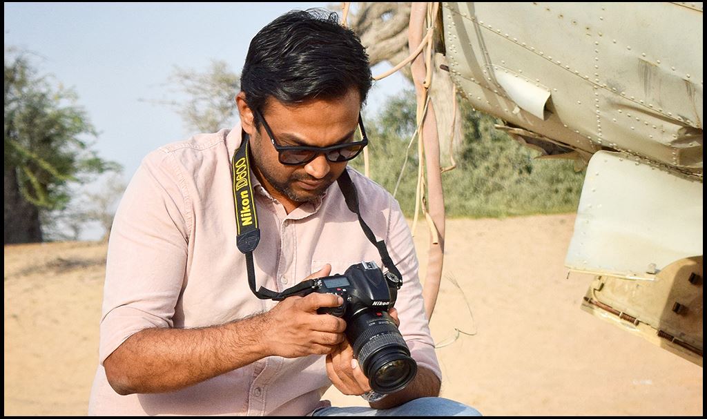ISG's Raees Ali looking at photos on a DSLR camera in a desert environment