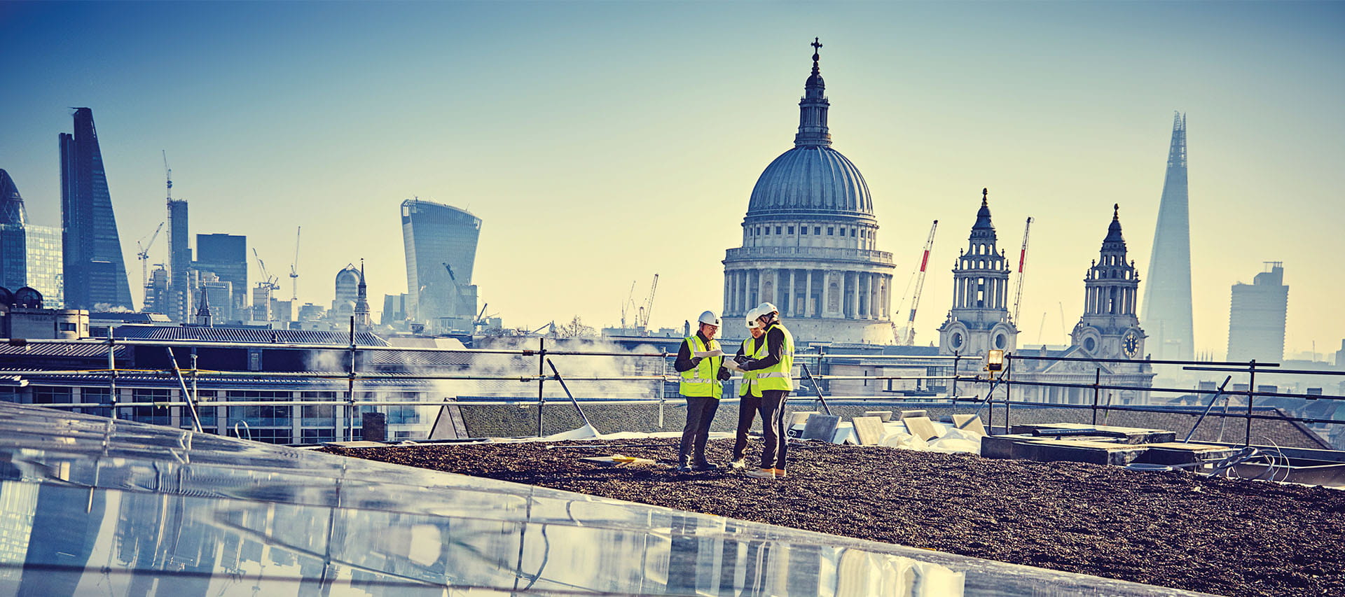 ISG construction workers looking at plans on rooftop site opposite St Paul's cathedral London