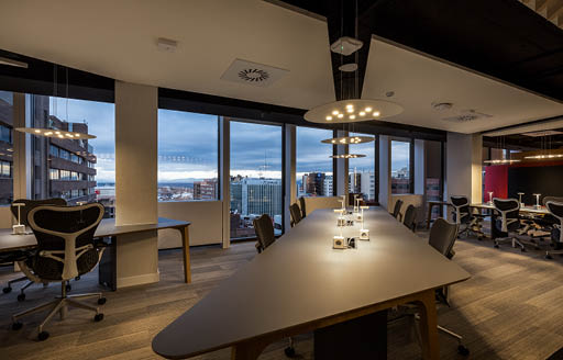 Interior of new refurbished office in Madrid for client, Citrix Systems with large table in open plan office with windows showing evening sky
