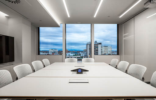 Interior modern meeting room with white table chairs, black monitor screen and windows revealing skyline in the Citrix Systems refurbishment