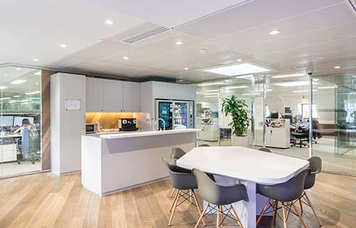 Office reception interior, wooden floors, with white desk with chairs and open plan office in distance