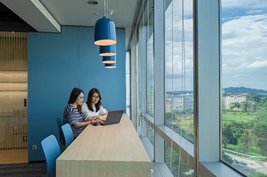 Two employees at a meeting table near a window overlooking a park in a modern office fit out by ISG