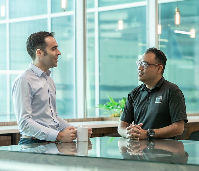 ISG Singapore Leroy Simon in conversation with another employee at a glass table in a modern office