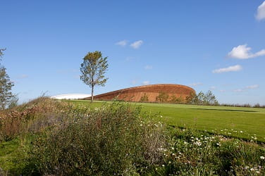 UK Olympic velodrome surrounded by green hill with tree and blue skies