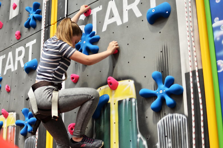 Interior female climber on climbing wall with coloured handholds