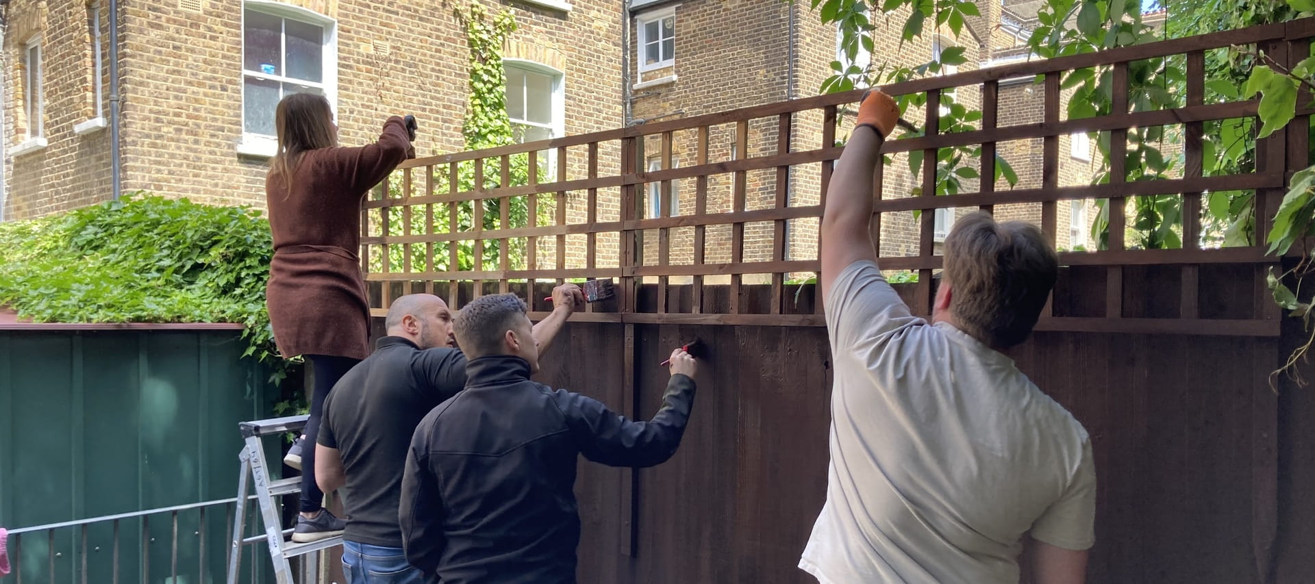 Group of ISG social value employees painting a fence in a community garden