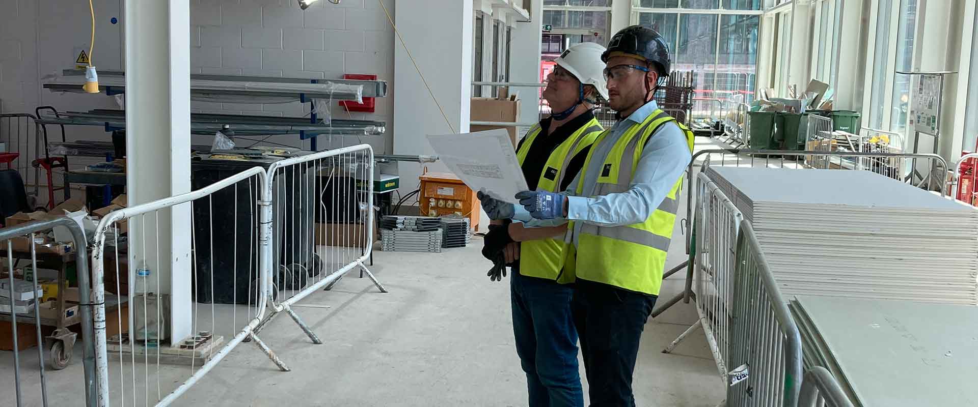 Two ISG employees in PPE looking at plans in the interior of a building under construction
