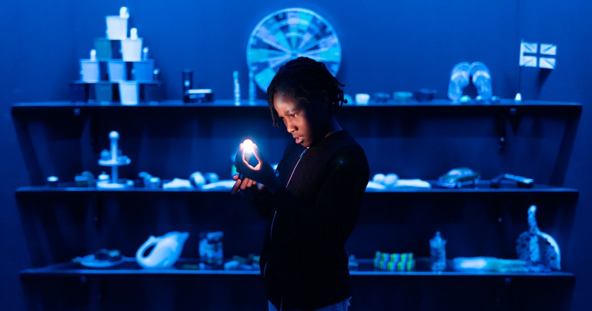 Child staring intently at an orb of light in front of other scientific objects at London Science Museum ISG